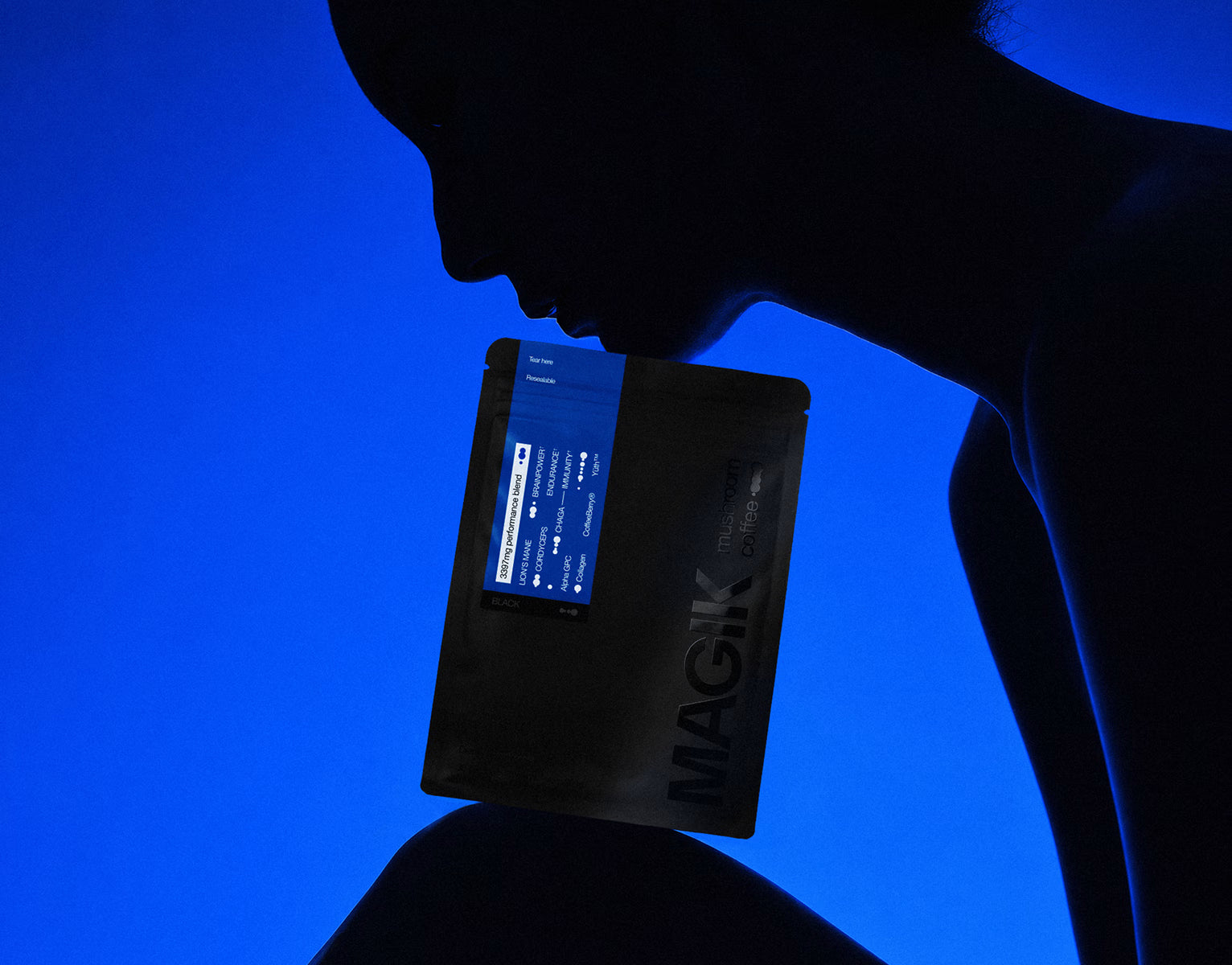 Person holding a black package with "MAGIK" branding against a blue background