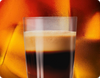 Glass of dark espresso coffee on a warm glowing background.