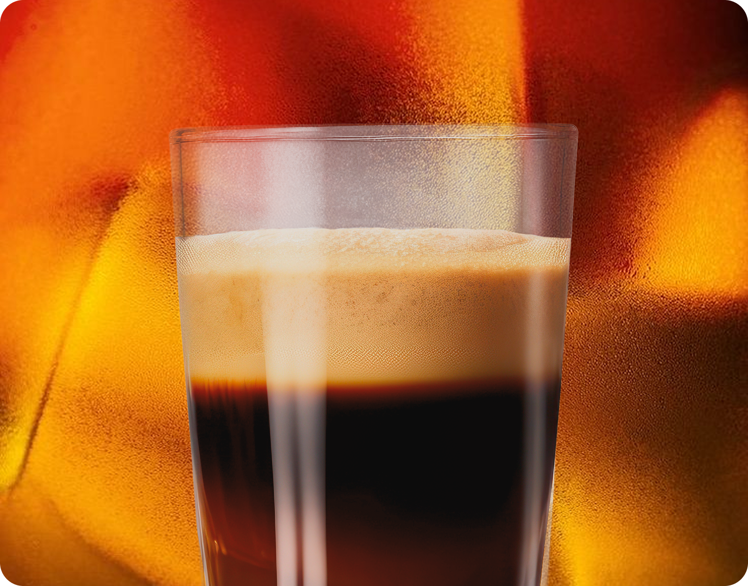 Glass of dark espresso coffee on a warm glowing background.